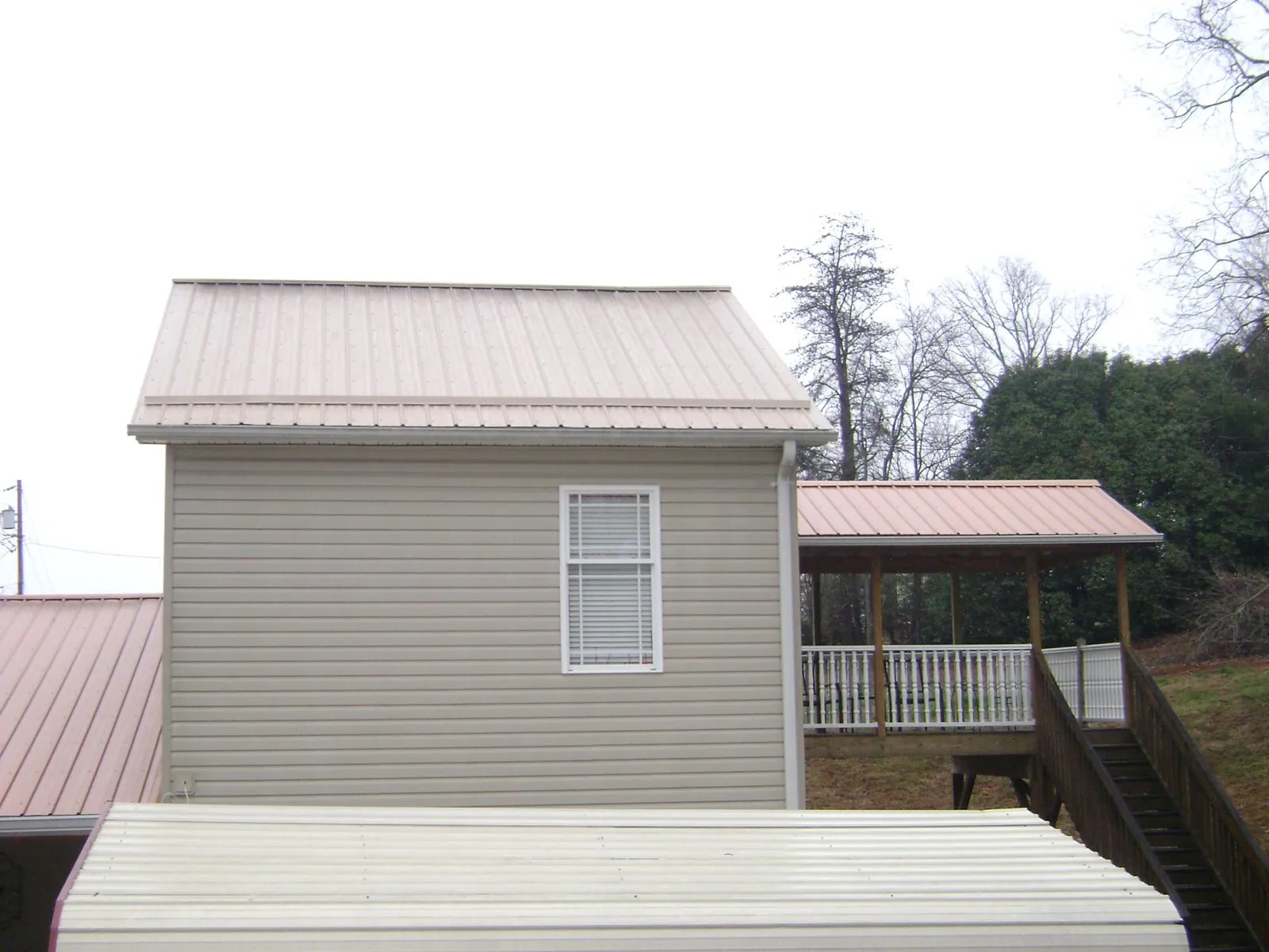 Tan metal roofs on a two story addition and attached porch, from a Roof Replacement job in Bremerton