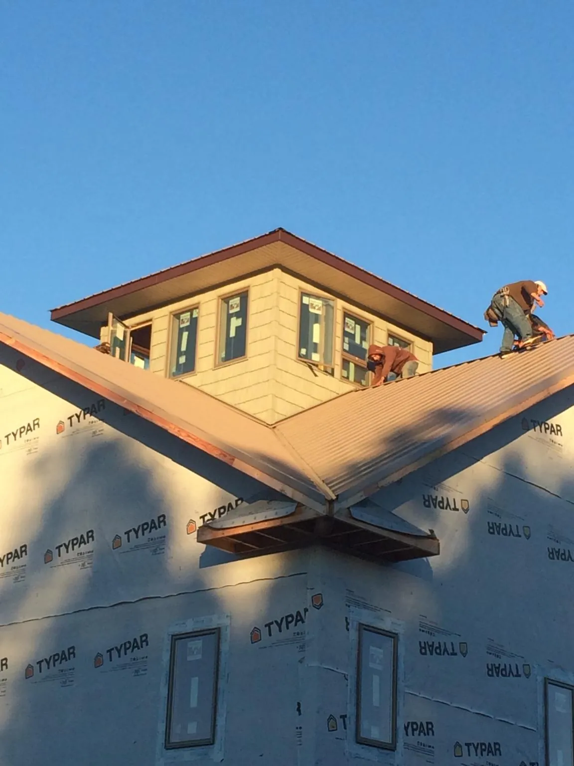 Roofers working around a rooftop cupola on a new metal roof at sunset — Roof Waterproofing in Bremerton by Roofing Brothers